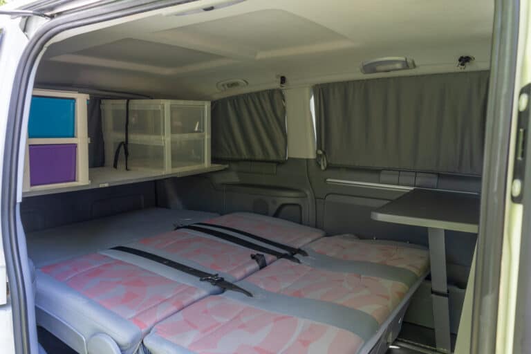 Intérieur de van aménagé avec lit et rangements.
