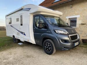 Camping-car moderne Peugeot garé devant une maison